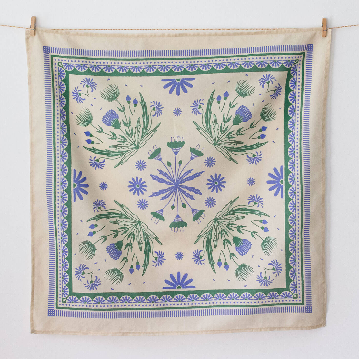 Decorative bandana with floral pattern hanging on a line against a white background