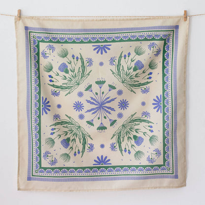 Decorative bandana with floral pattern hanging on a line against a white background