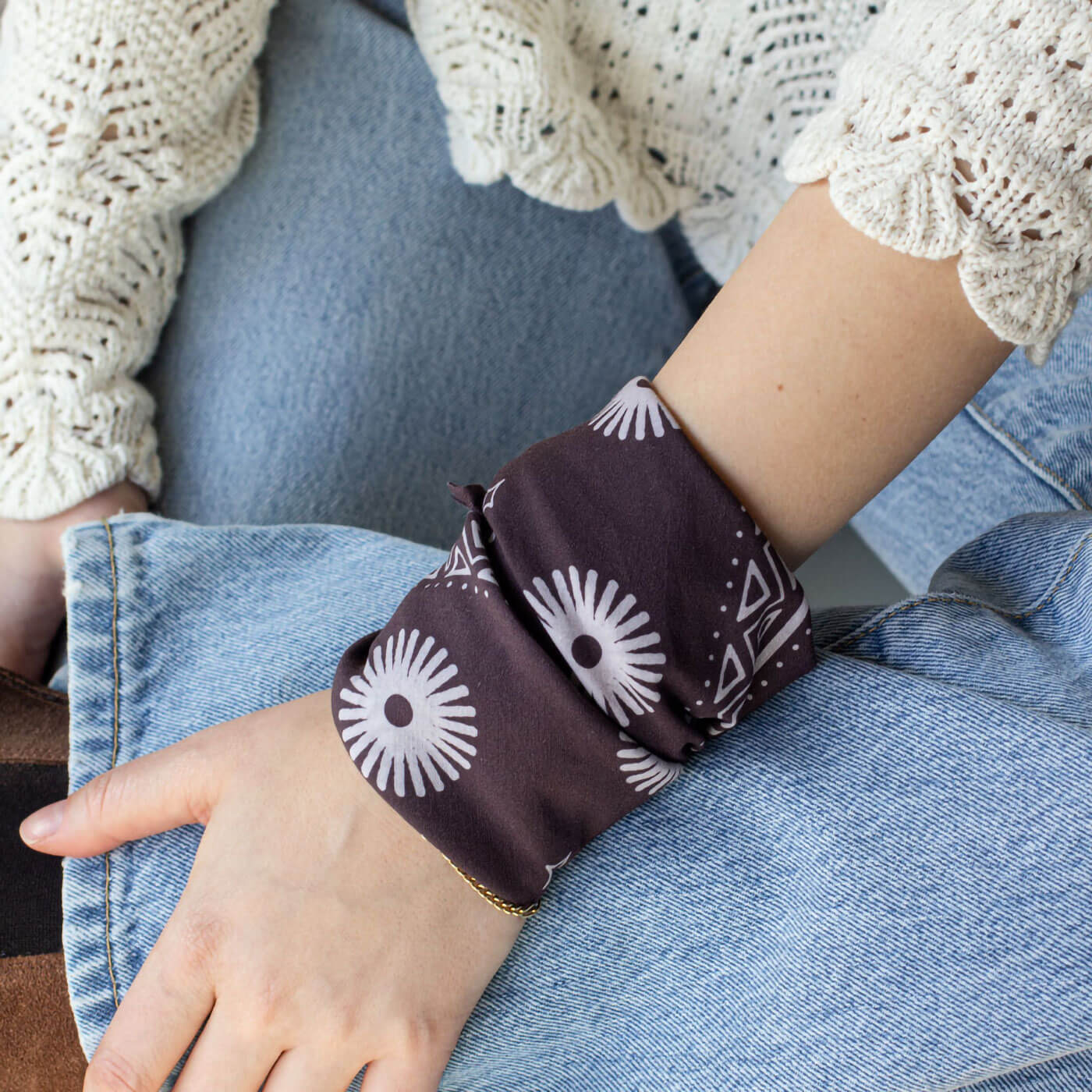 Woman wearing a dark purple bandana with white floral patterns.