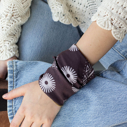 Woman wearing a dark purple bandana with white floral patterns.