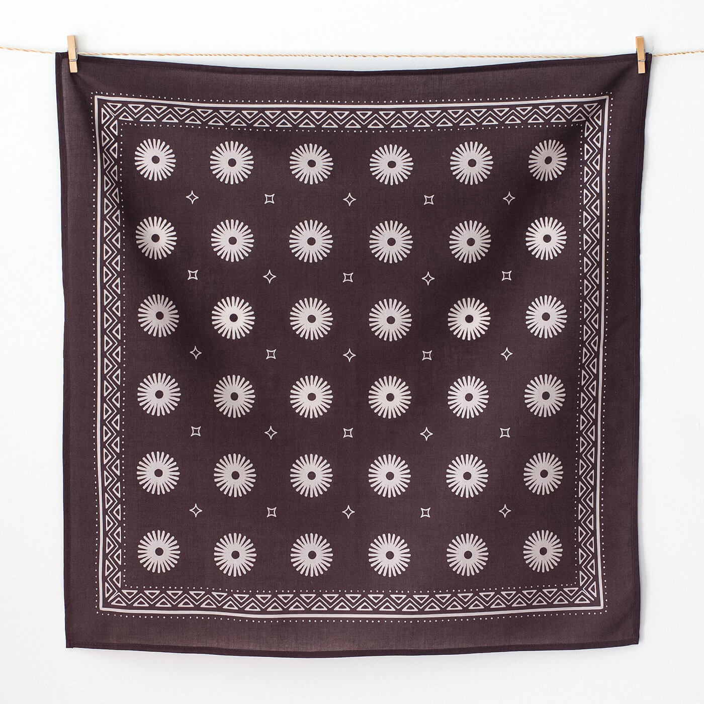 Purple bandana with white geometric pattern hanging on a line