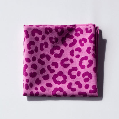 Folded pink bandana with leopard print pattern on a light gray background