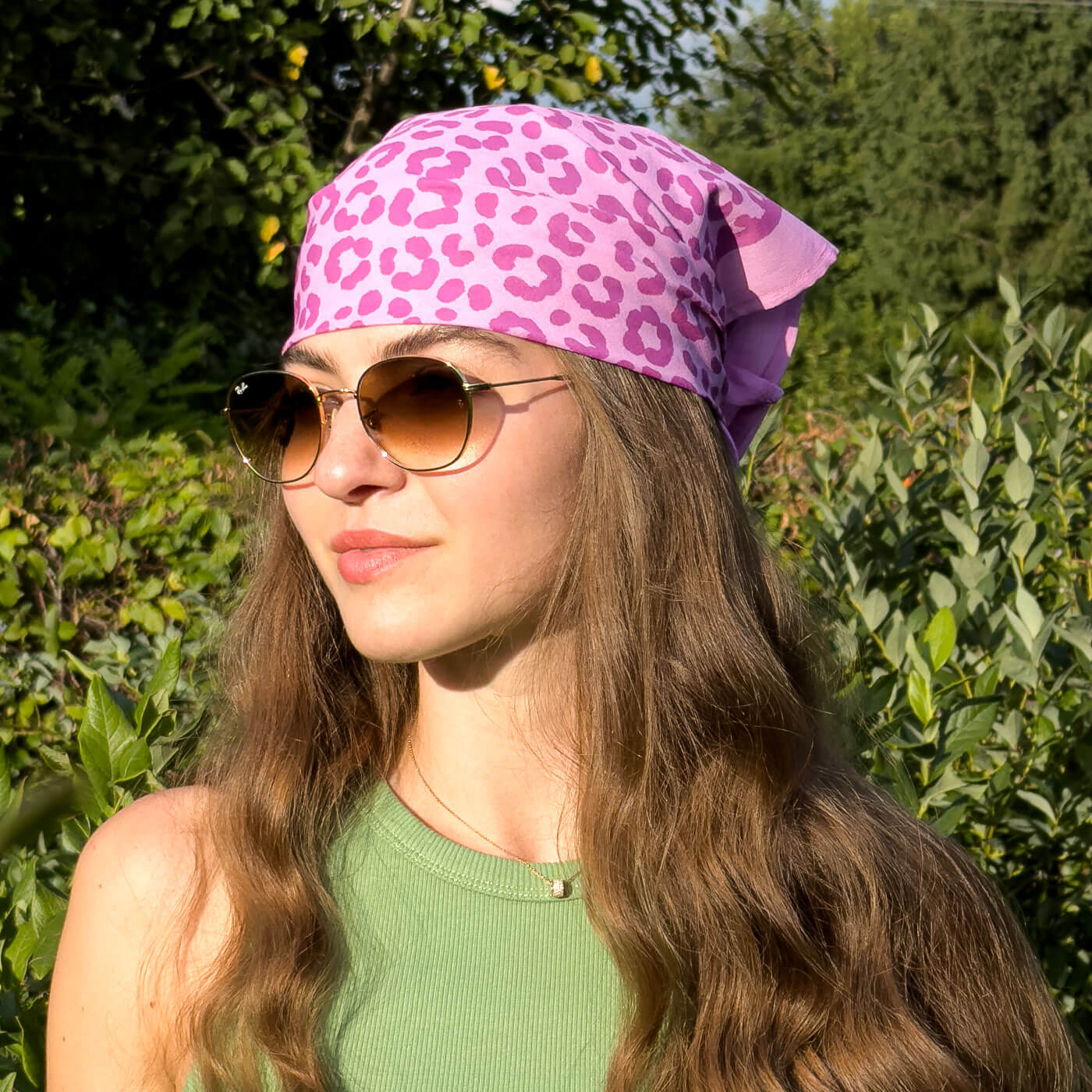 Woman wearing a pink leopard print headscarf and sunglasses outdoors