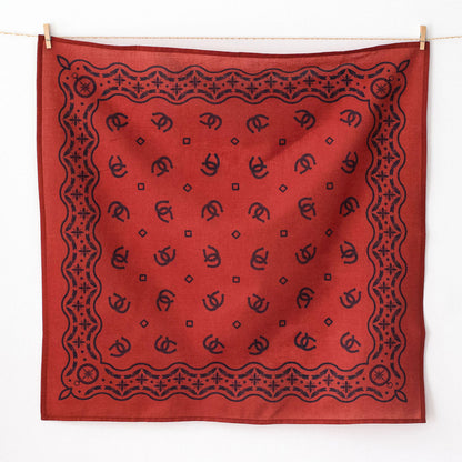 Red bandana with black patterns hanging on a line against a white background
