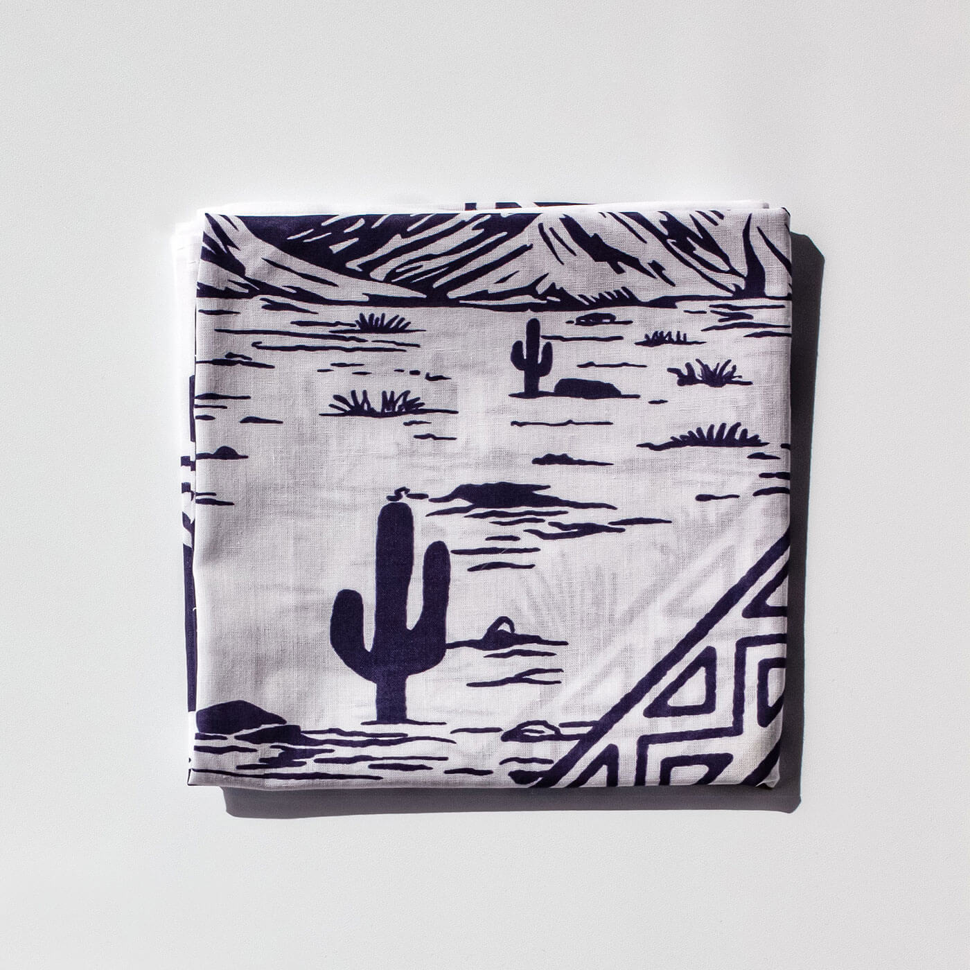Folded bandana with desert landscape pattern on a light gray background