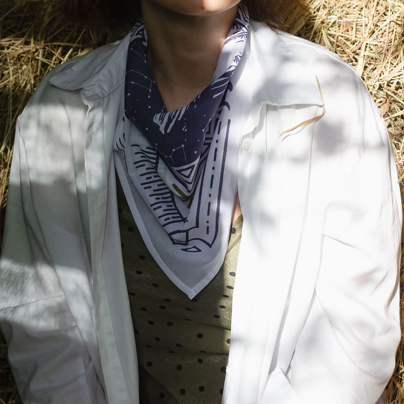 Woman wearing a white shirt with a patterned bandana in a sunlit outdoor setting